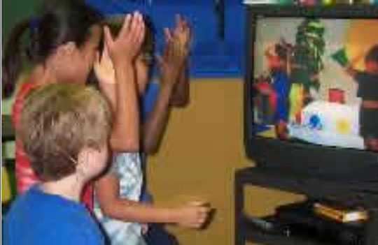 Young students watch a video on a TV in class.