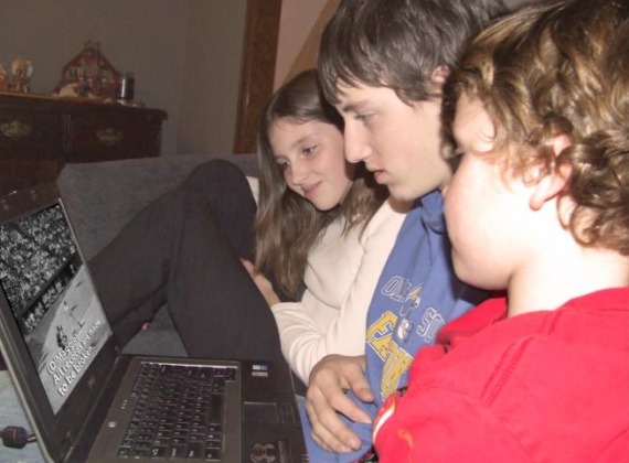 Three children watch a video on a laptop.