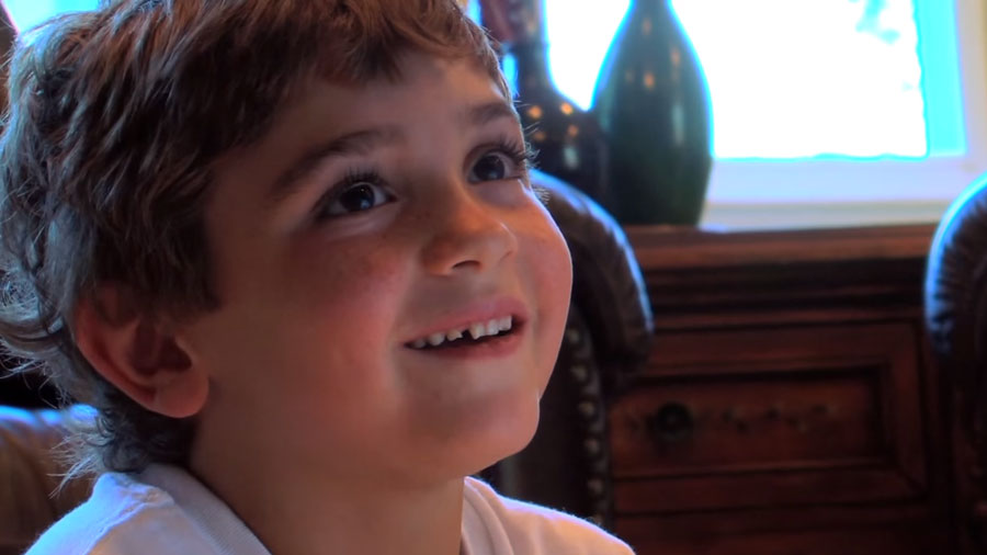 A young boy smiles as he watches television.