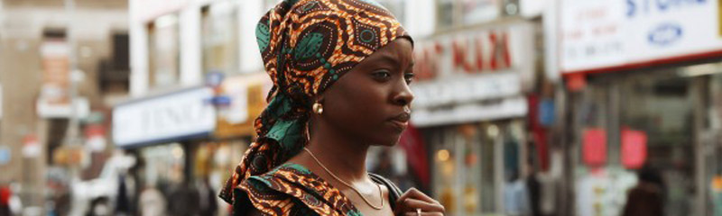 A young black woman walks down a city street.