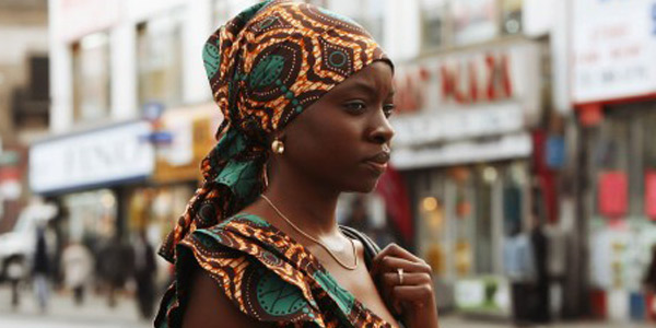 A young black woman walks down a city street.