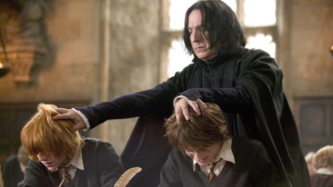 Professor Snape pushes down the heads of students Harry Potter and Ron Weasley toward their school books.