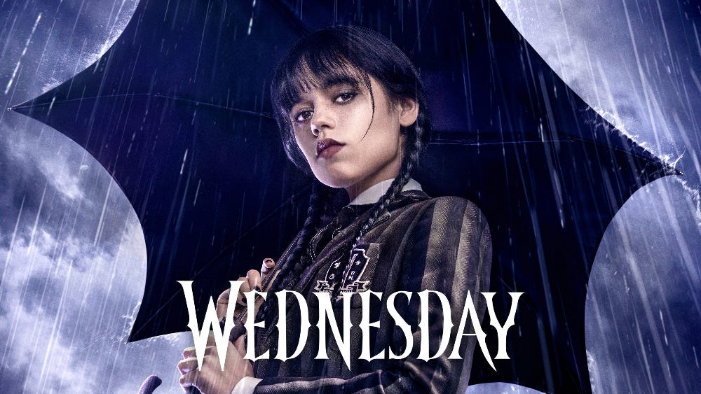 A young girl with dark hair and long braids holds an umbrella under a dark, rainy sky. Text: Wednesday.