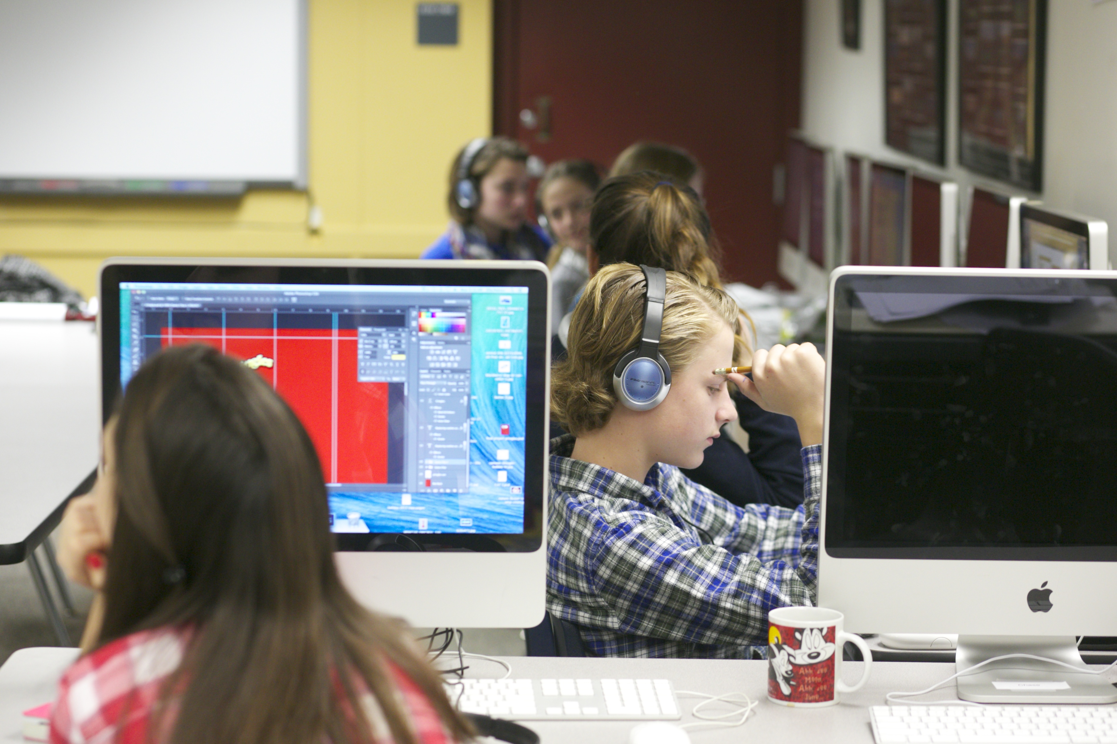 Students ina classroom sit at computers and wear headphones.