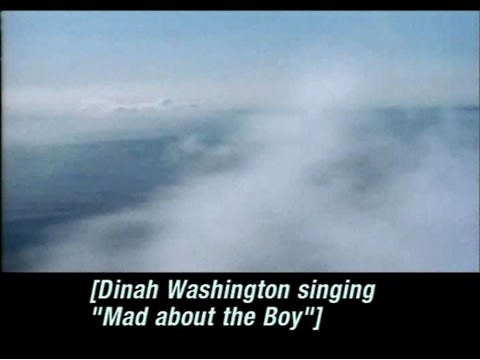 Video still of clouds over the ocean. Caption reads: [Dinah Washington singing "Mad about the Boy"].