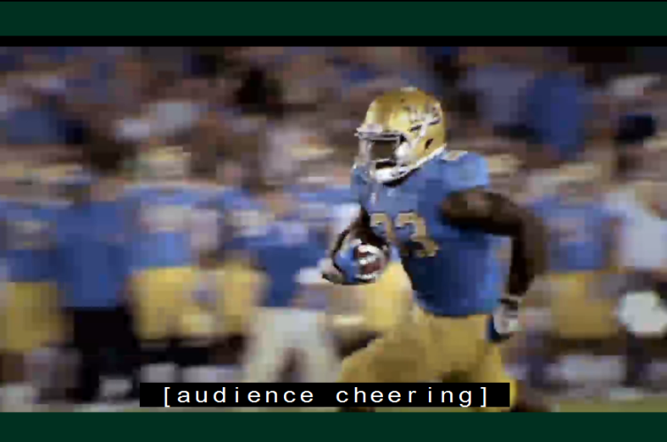Video still of football game with man running with the ball. Caption reads: [audience cheering].