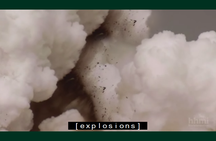 Video still of thick smoke. Caption reads: [explosions].