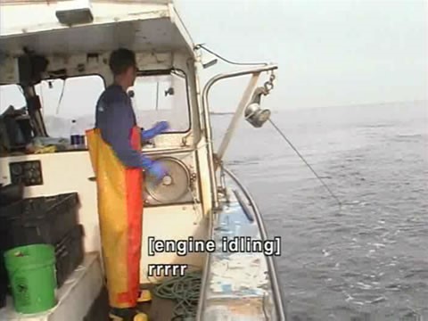 Video still of fisherman on a boat. Caption reads: [engine idling] rrrrr.