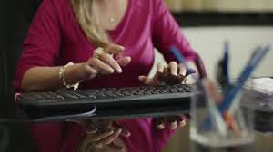 A woman types at her desk.