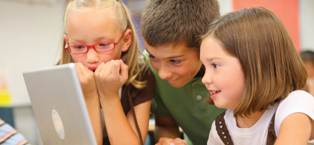 Children look happily into an open laptop