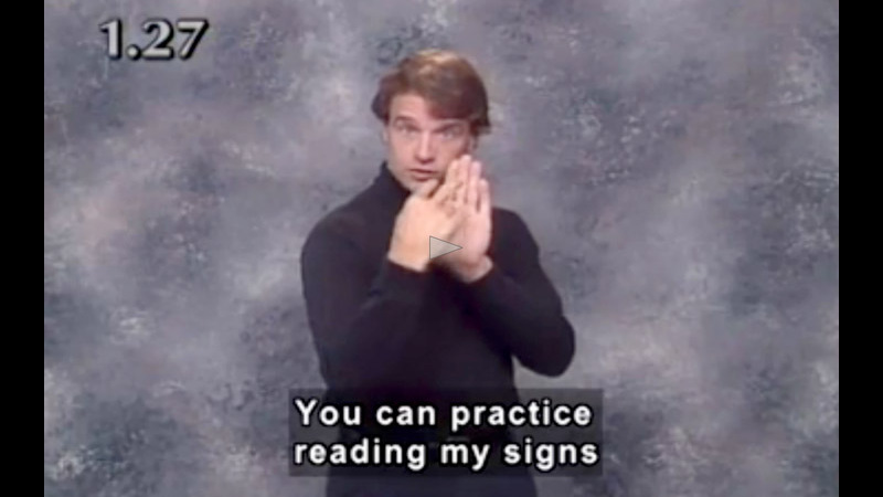 A video still of someone doing Sign Language with the closed caption reading 'You can practice reading my signs.'