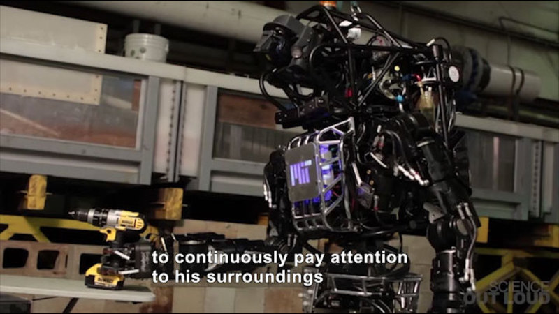 A humanoid robot holding a drill. Caption: to continuously pay attention to his surroundings