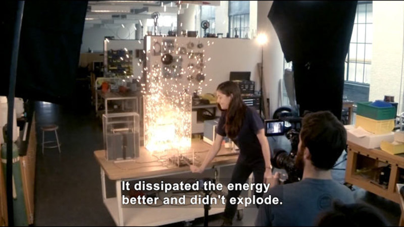 People in a lab setting, filming an explosion that is occurring in a container. Caption: It dissipated the energy better and didn't explode.