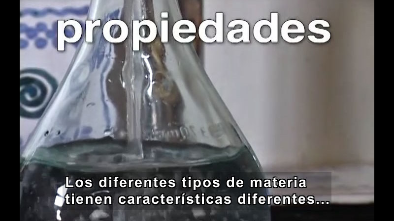 Glass beaker with clear liquid. Spanish captions.