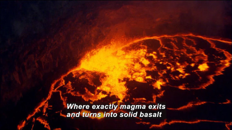 Glowing lava as seen from above. Caption: Where exactly magma exits and turns into solid basalt