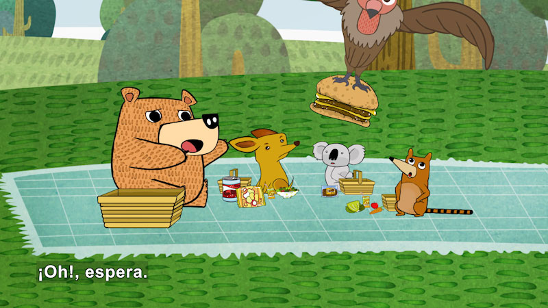 Cartoon of a bear and other animals having a picnic and looking dismayed. A large bird has swooped down and taken a hamburger from their picnic. Spanish captions.