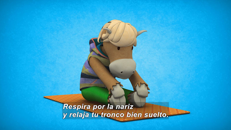 Cartoon cow on a yoga mat stretching to touch its toes. Spanish captions.