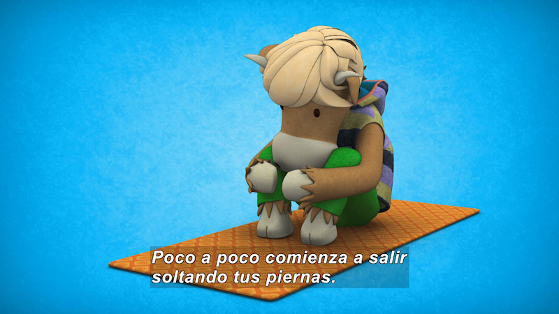 Cartoon cow on a yoga mat stretching to hug its knees. Spanish captions.