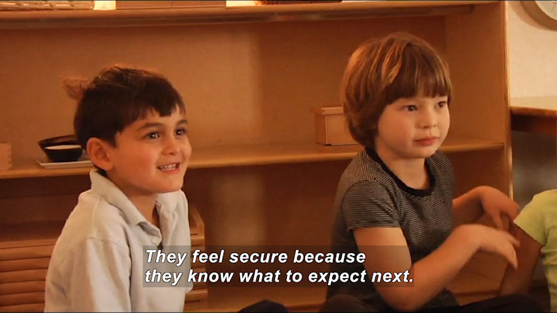 Kids sitting on the floor in a classroom setting. Caption: They feel secure because they know what to expect next.