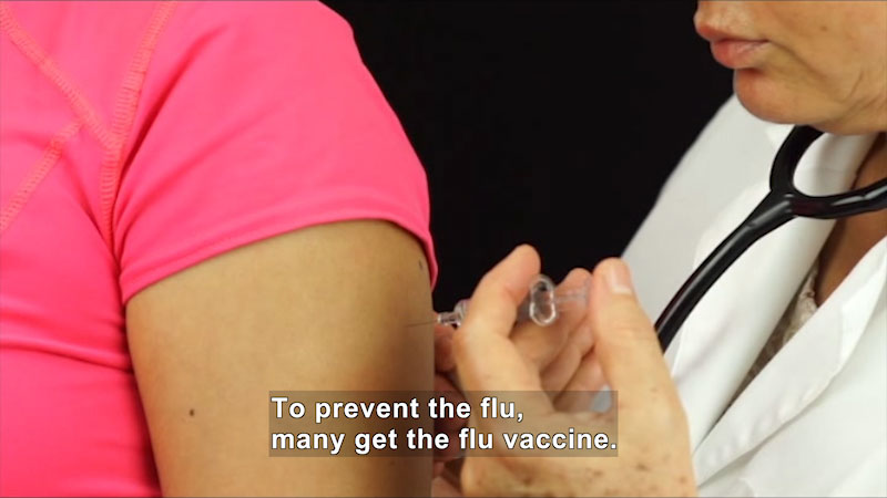 Doctor injecting patient in their upper arm. Caption: To prevent the flu, many get the flu vaccine.