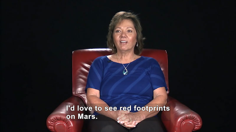 Woman speaking. Caption: I'd love to see red footprints on Mars.