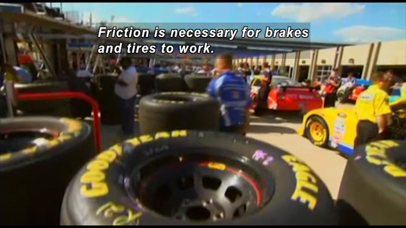 Pit crew station filled with tires at a racetrack. Caption: Friction is necessary for breaks and tires to work.