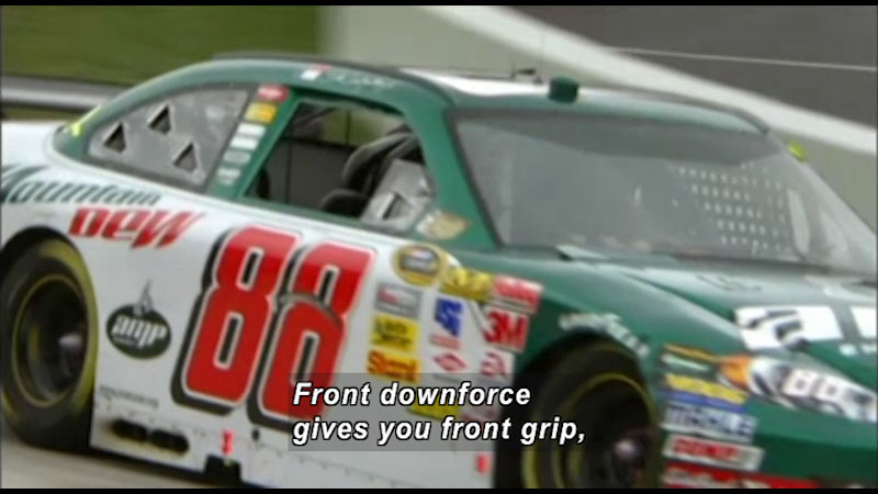 Race car on a track. Caption: Front downforce gives you front grip,
