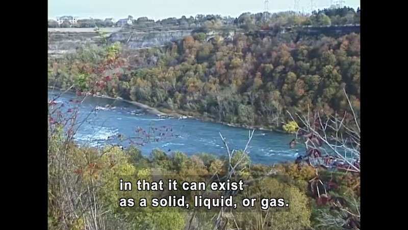 River with forested banks. Caption: in that it can exist as a solid, liquid, or gas.