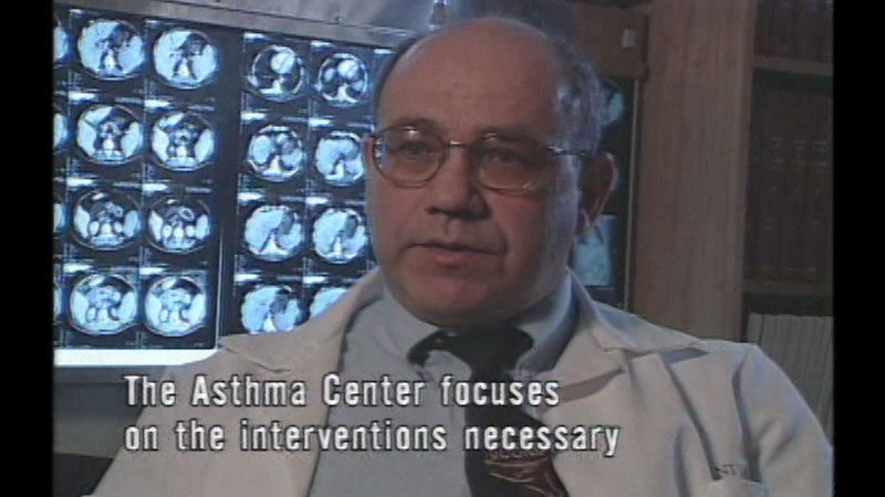 Person speaking while sitting in front of a light board displaying imaging results. Caption: The Asthma Center focuses on the interventions necessary