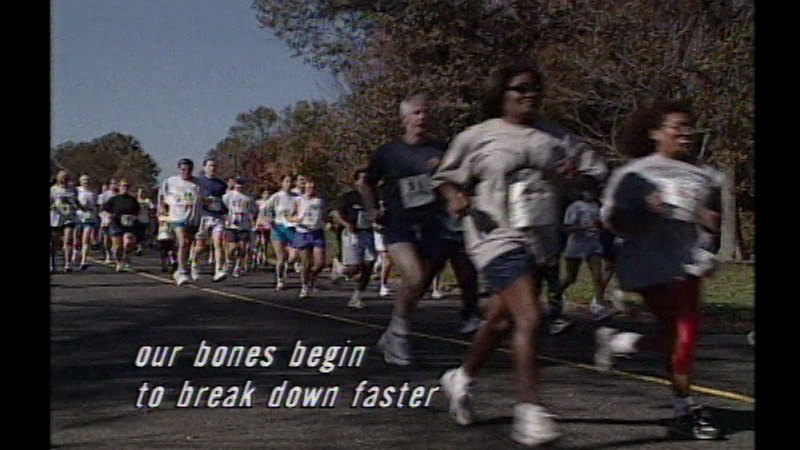 People with race bibs running down the street. Caption: Our bones begin to break down faster
