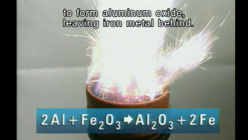 Sparks flying out of a small container. Caption: to form aluminum oxide, leaving iron metal behind. 