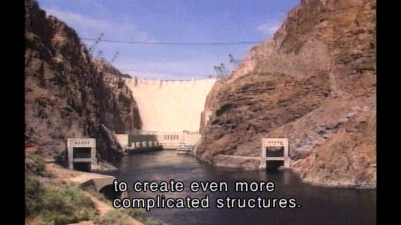 Manmade dam as seen from below. Caption: to create even more complicated structures.