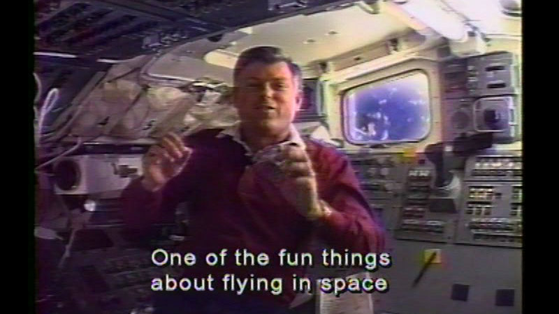 Person floating in a chamber with switches, buttons, and lights on the walls. Caption: One of the fun things about flying in space
