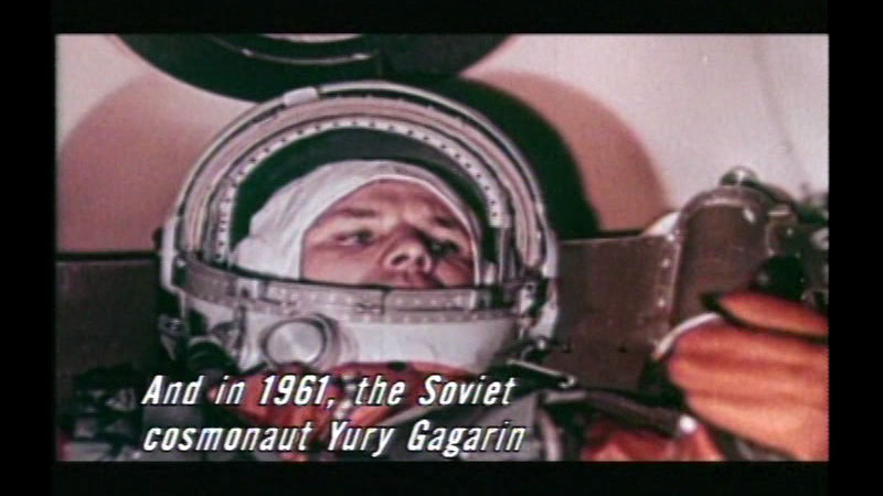 Astronaut in a space suit with the face plate open. Caption: And in 1961, the Soviet cosmonaut Yuri Gagarin
