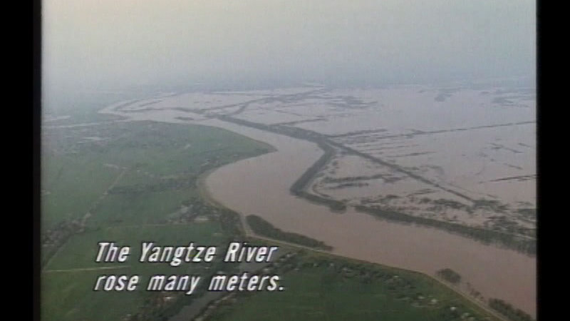 Green fields partially flooded with water from a winding brown river. Caption: The Yangtze River rose many meters.