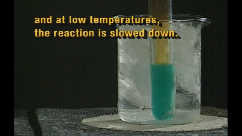 Test tube with aqua liquid in the bottom is immersed in ice water. Caption: and at low temperatures, the reaction is slowed down.