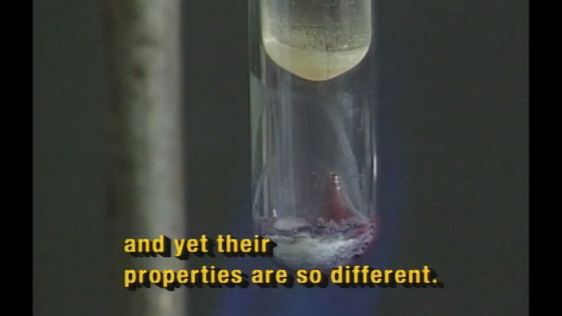 A large beaker with a substance in the bottom, a smaller beaker suspended above it. Caption: and yet their properties are so different.