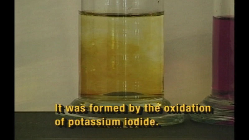 Beaker of liquid with a yellow substance dissolving. Caption: It was formed by the oxidation of potassium iodide.