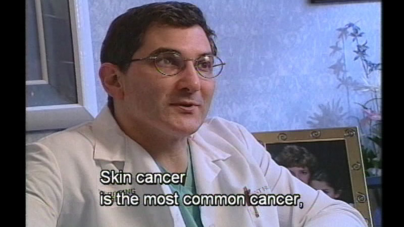 Person in a white coat talking. Caption: Skin cancer is the most common cancer,