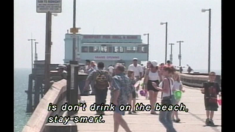 People on a pier on a sunny day. Caption: is don't drink on the beach, stay smart.