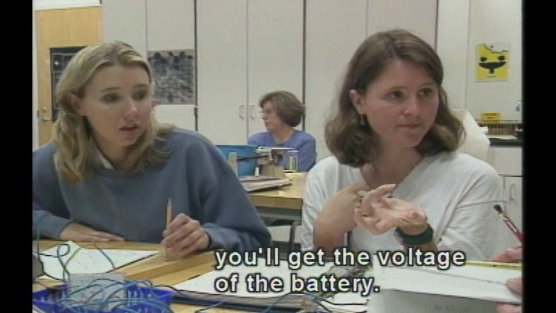 Students in a classroom setting. Caption: you'll get the voltage of the battery.
