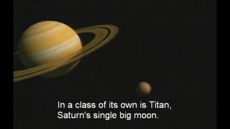 Brown, tan, and beige banded planet with rings. A smaller spherical object is next to it. Caption: In a class of its own is Titan, Saturn's single big moon.