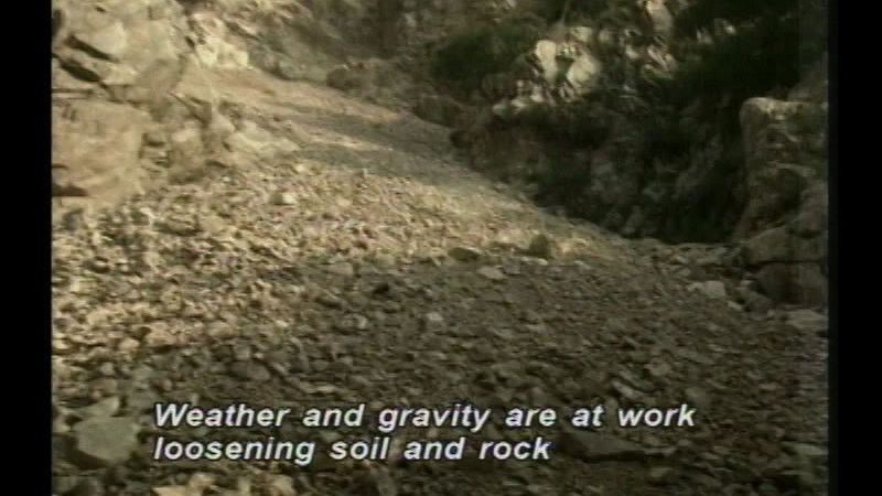Rocky slope covered in scree. Caption: Weather and gravity are at work loosening soil and rock