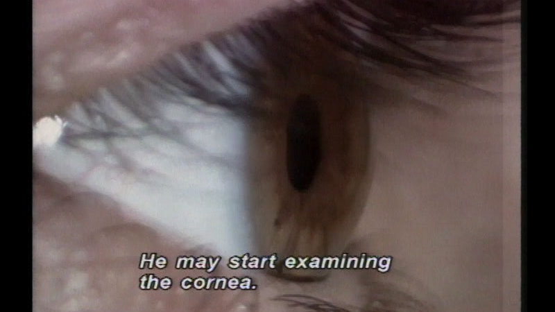 Closeup of the human eye. Caption: He may start examining the cornea.