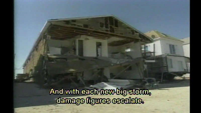 House on the beach with one wall falling off. Caption: And with each new big storm, damage figures escalate.