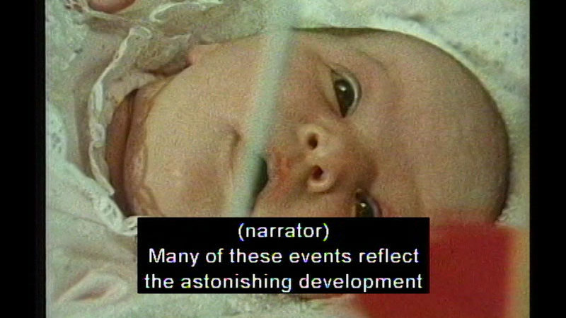 Closeup of a baby's face. Caption: (narrator) Many of these events reflect the astonishing development