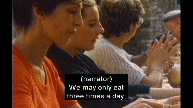 People sitting at a table. Caption: (narrator) We may only eat three times a day,