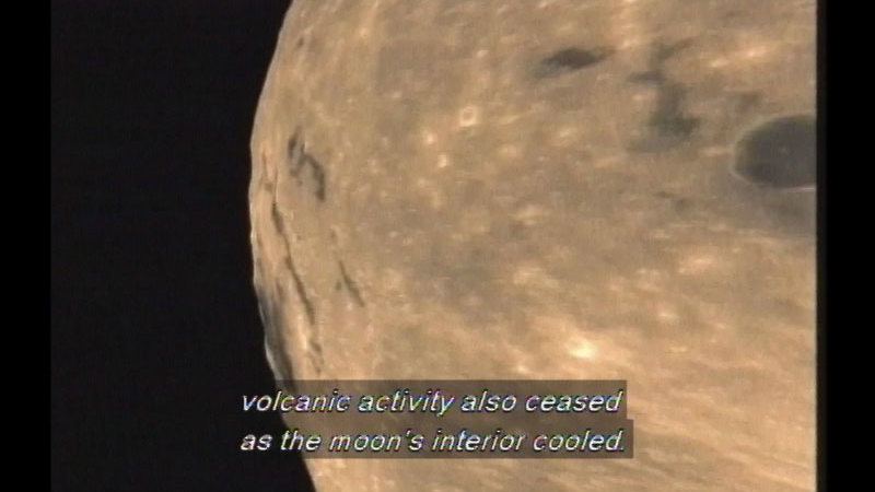 The surface of the moon in relief against the black background of space. Caption: volcanic activity also ceased as the moon's interior cooled.