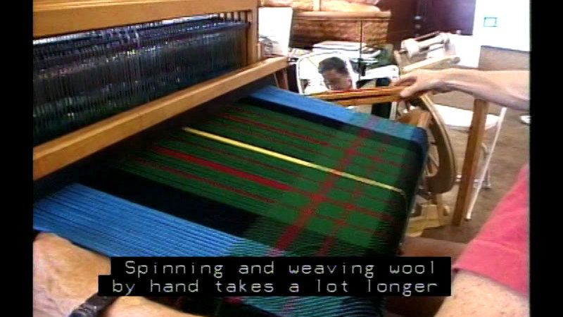 Person at a loom with a partially finished piece of patterned fabric. Caption: Spanning and weaving wool by hand takes a lot longer