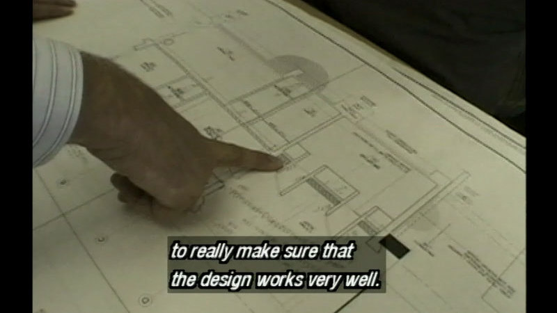 Hand pointing at part of a blueprint. Caption: to really make sure that the design works very well.